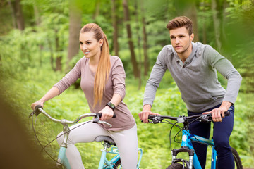 Obraz premium Cheeful loving couple cycling in park