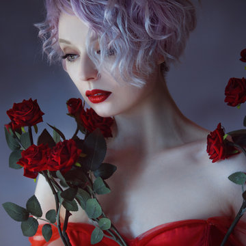 Fashion photo of young magnificent woman with red roses. Textured background.