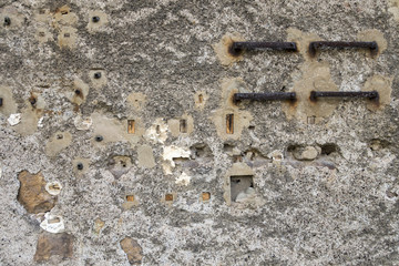 Remains of an old electrical installation mounted on a cracked wall.