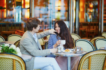 Couple drinking coffee and eating croissants in Parisian cafe