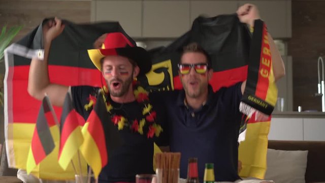 two german fans cheering at home for germany