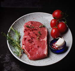 Raw striploin beef steak on black background