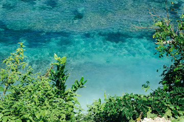 Aerial view of tropical forest, empty white sand beach and vivid blue sea reef in Bali, Indonesia.
