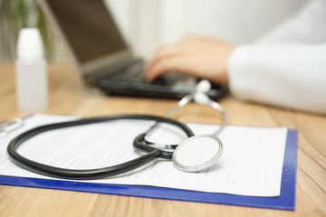 doctor in blurred background is typing on laptop keyboard