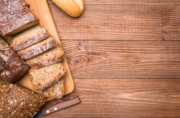 Assortment of baked bread on wooden table background.