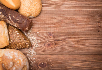 Assortment of baked bread on wooden table background.