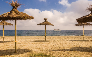 Desert beach, straw sunshades, sea, blue sky and touristic speed