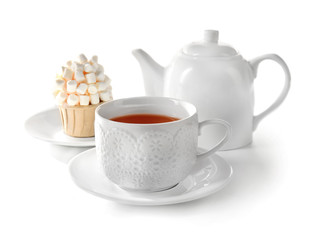 Cup of tea with tasty cupcake and teapot, isolated on white