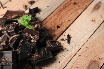 Chocolate pieces with mint leaves on wooden background