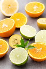 Fototapeta premium Mixed citrus fruit lemons, orange, kiwi, limes on a gray backgro