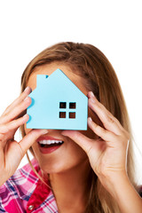 Woman peeks through the window of a paper house