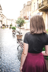 A young girl with beautiful hair and dress a black shirt waiting for friends. She straightens hair at school. The girl walk in a city. Pretty Girl. Wind develops hair