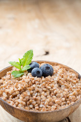 Buckwheat porridge in a bowl with mint leaves and blueberries.
