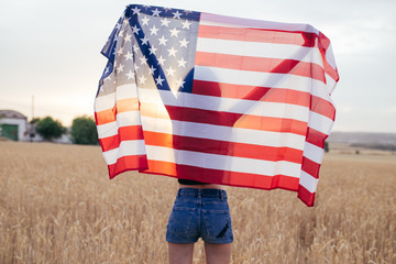 Girl with american flag smiling in the sunset. Young woman playi