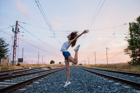 Young girl smiling and playing alone on the rails of an old aban