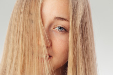 Naklejka premium Beauty shoot of a young pretty girl nude. Blue eyes, blond hair, wearing no make-up in her perfect clear skin. Cosmetic advertisement style. Natural scandinavian face of a woman looking at the camera