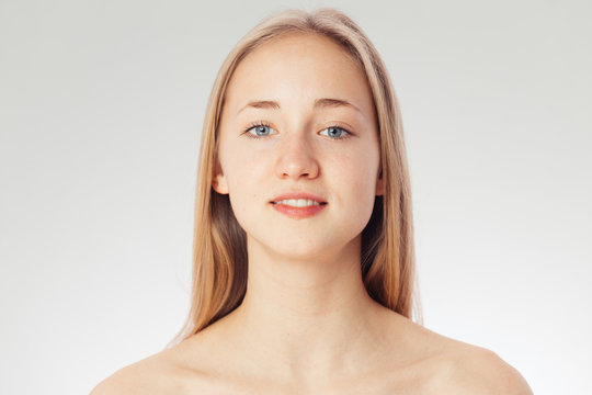 Beauty shoot of a young pretty girl nude. Blue eyes, blond hair, wearing no make-up in her perfect clear skin. Cosmetic advertisement style. Natural scandinavian face of a woman looking at the camera