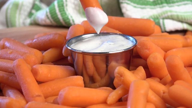 Dipping baby carrots into ranch dressing

