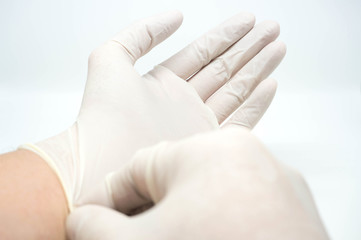 putting on disposable sterile white gloves on white background