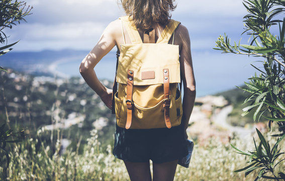 Hipster young girl with bright backpack looking at a map and poining hand the travel plan. View tourist traveler on background mountain, sea. Mock up for text message