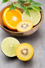 Obraz na płótnie Canvas Mixed citrus fruit lemons, orange, kiwi, limes on a gray backgro