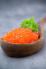 Salmon caviar with spoon on gray background.