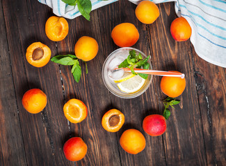 Cold fresh lemonade and apricots on wood background