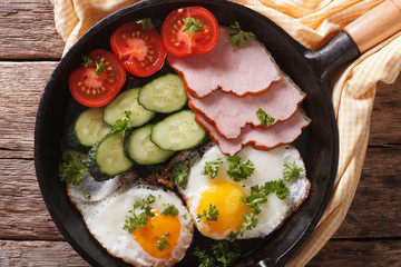 fried eggs with ham, tomatoes and cucumbers close-up. Horizontal top view 
