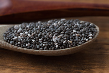 Black Chia seeds in wooden spoon extreme closeup