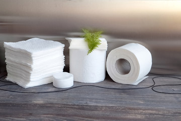 White kitchen paper towel, toilet paper, paper tissues, cotton disks on a dark wooden table