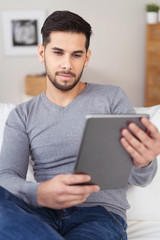 entspannter mann sitzt auf dem sofa und schaut auf tablet