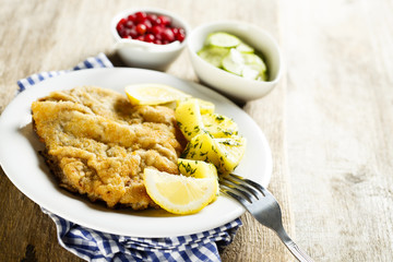 Classic schnitzel with lemon, potato, cucumber salad and berries