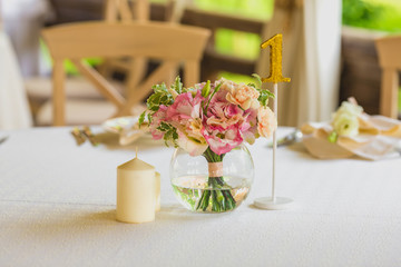Stylish beautiful luxury wedding decor with a lot of flowers, candles and number on the tables in restaurant hall