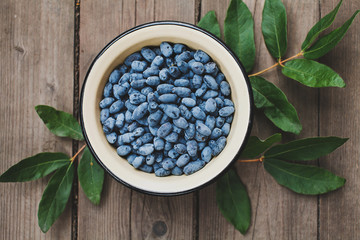Honeysuckle's berries in bowl on wooden background