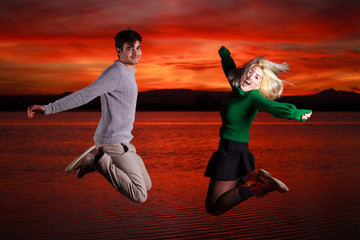 chico y chica saltando en el muelle del lago al atardecer