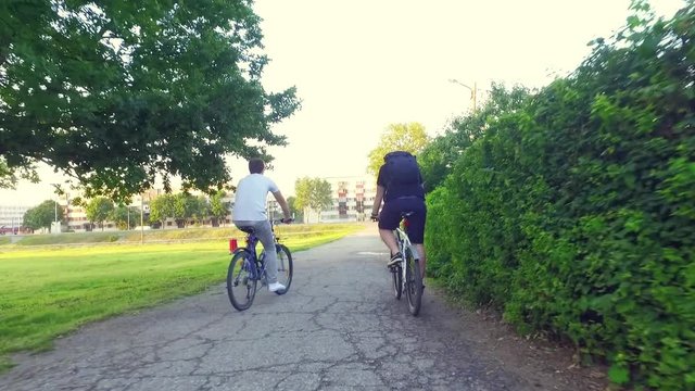 Slow motion steadicam shot of two healthy men peddling with cycling city bicycle