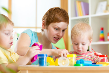 Obraz na płótnie Canvas mother teaches her children to work with colorful playdough