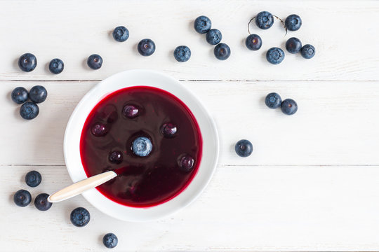 blueberry soup on wooden white background, top view, flat lay