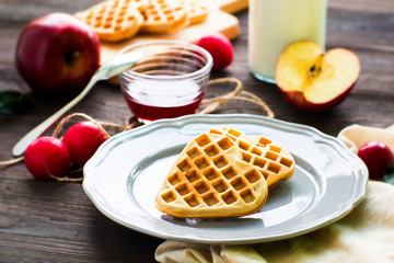 Heart-shaped waffles with sause on dark wooden background. Morning breakfast