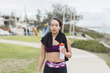 Beautiful fitness athlete woman resting drinking water after workout