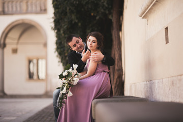 Beautiful couple, man, girl with long pink dress posing in old castle near columns. Krakow Vavel