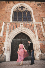 Fototapeta na wymiar Gorgeous wedding couple, groom and bride with pink dress walking in the old city of Krakow