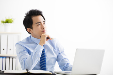 young businessman working on laptop and thinking