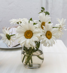 Bouquet of white daisies in a glass vase on table
