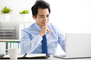 smiling young business man working on laptop