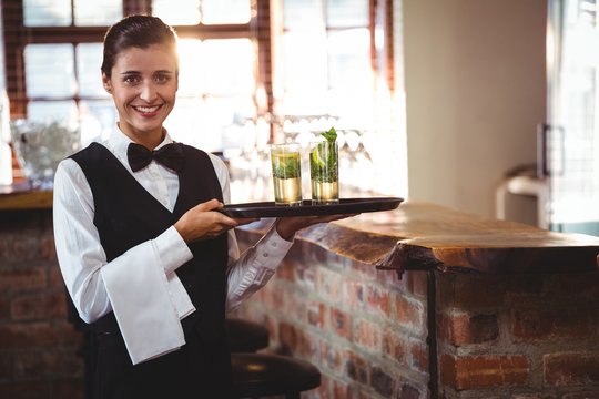 Female bartender holding a serving tray with two cocktail glass