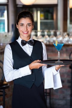 bartender holding serving tray with glass of cocktail