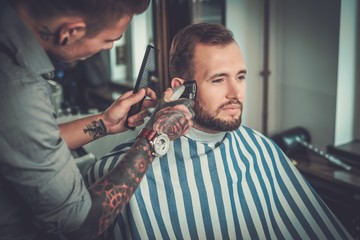 Confident man visiting hairstylist in barber shop.