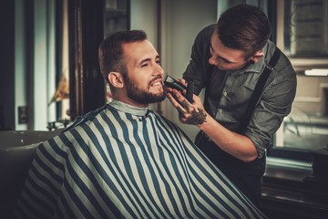 Confident man visiting hairstylist in barber shop.