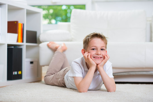 Happy Little Boy Lying On Floor